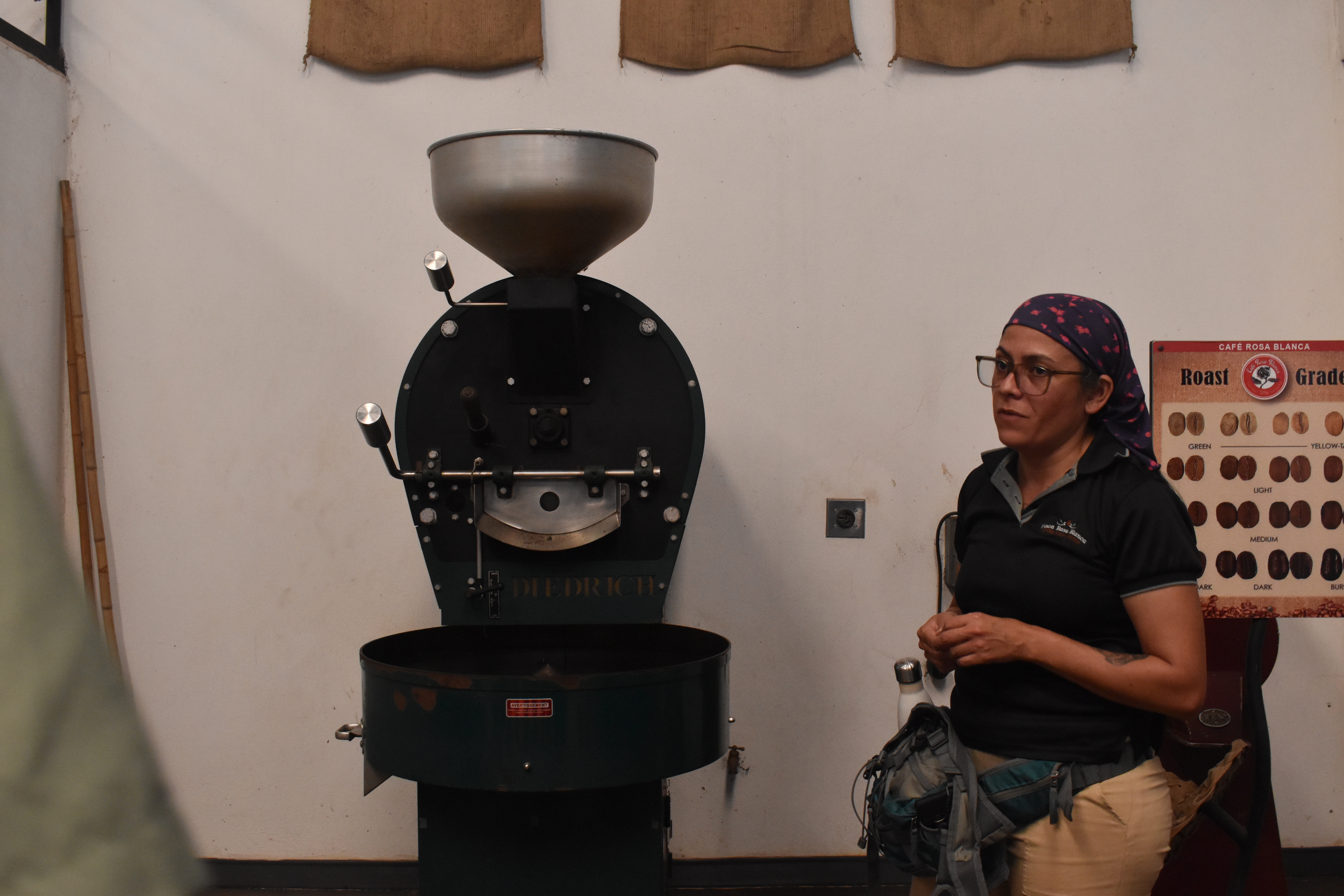 Coffee roasting machine inside a roasting room, with a worker standing beside the equipment during a demonstration.